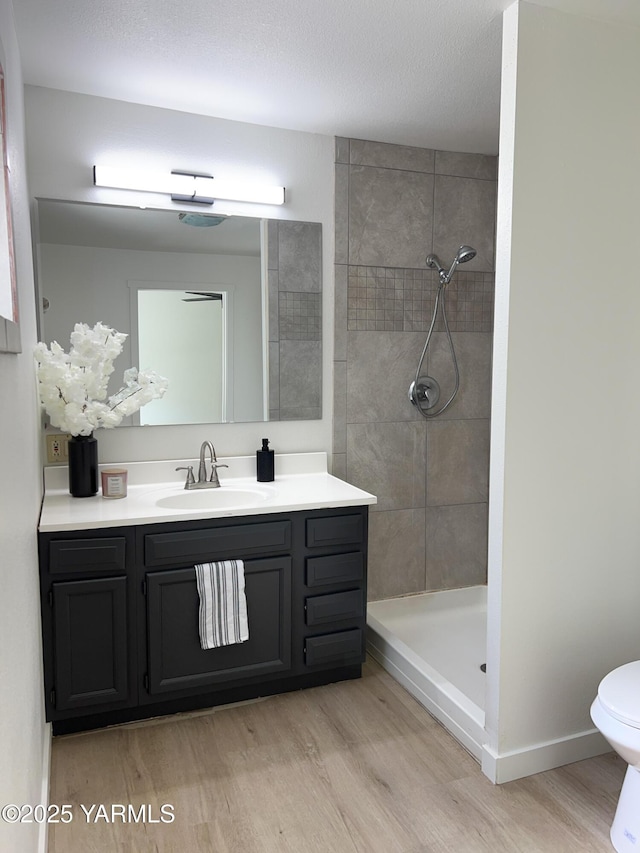 409 Elm Ave, Grandview, WA 98930 - bathroom featuring wood finished floors, vanity, toilet, and a tile shower