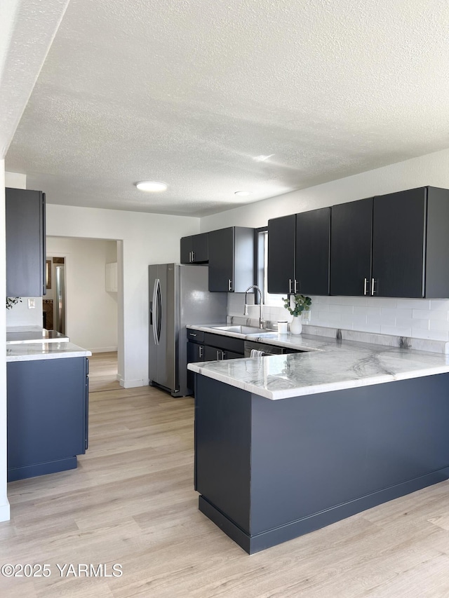 409 Elm Ave, Grandview, WA 98930 - kitchen featuring a sink, a peninsula, a textured ceiling, dark cabinets, and stainless steel fridge