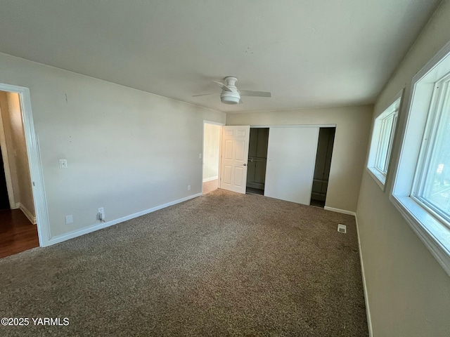 unfurnished bedroom with a closet, dark carpet, and baseboards