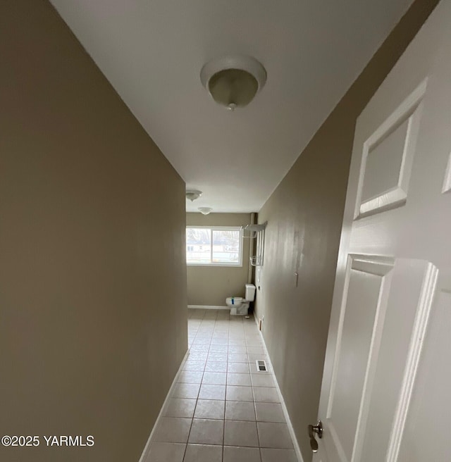 corridor with light tile patterned floors and baseboards