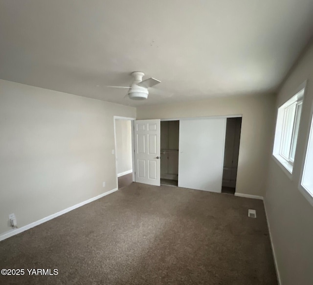 unfurnished bedroom with visible vents, baseboards, dark colored carpet, and a closet
