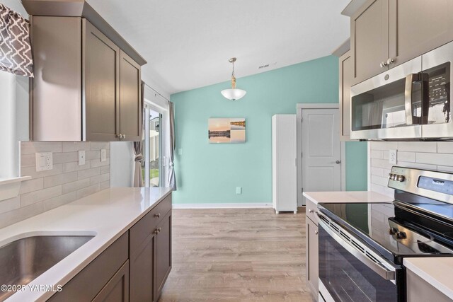 5301 Sage Way, Yakima, WA 98901 - kitchen featuring stainless steel appliances, vaulted ceiling, backsplash, light wood-style floors, and light countertops