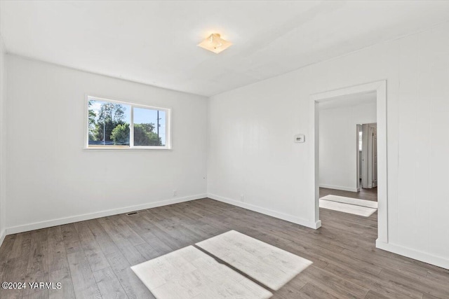 empty room with dark wood-type flooring and baseboards