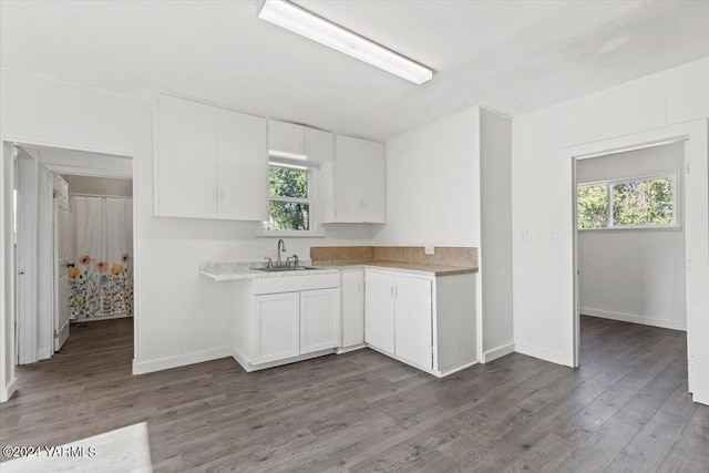 kitchen featuring white cabinets, dark wood-style flooring, light countertops, and a sink