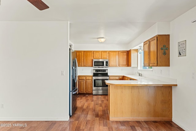 604 N 57th St, Yakima, WA 98901 - kitchen featuring a peninsula, a sink, wood finished floors, light countertops, and appliances with stainless steel finishes