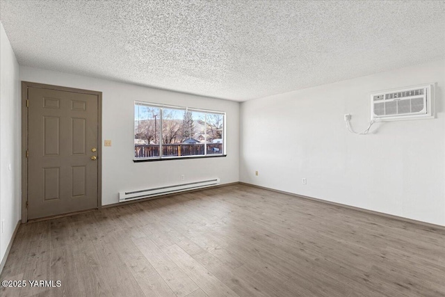 interior space featuring a baseboard heating unit, a textured ceiling, wood finished floors, and a wall mounted AC