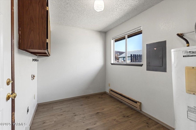 spare room with electric panel, baseboard heating, water heater, wood finished floors, and a textured ceiling