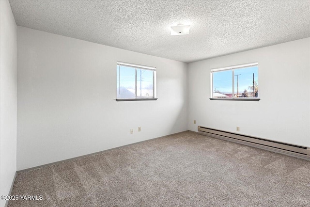 spare room with a wealth of natural light, a textured ceiling, a baseboard heating unit, and carpet