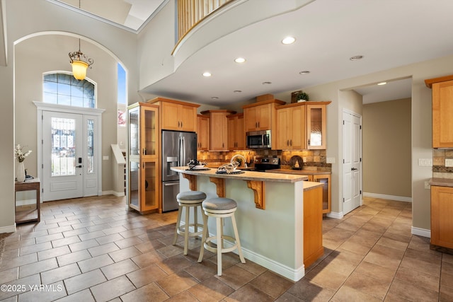 8704 Meadow Ln, Yakima, WA 98908 - kitchen with stainless steel appliances, backsplash, a breakfast bar area, a kitchen island, and light tile patterned floors