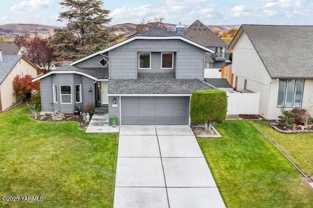 view of front of home featuring an attached garage, fence, concrete driveway, roof with shingles, and a front yard