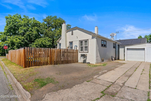 319 S 14th Ave, Yakima, WA 98902 - view of side of home featuring asphalt driveway, stucco siding, fence, a chimney, and a garage