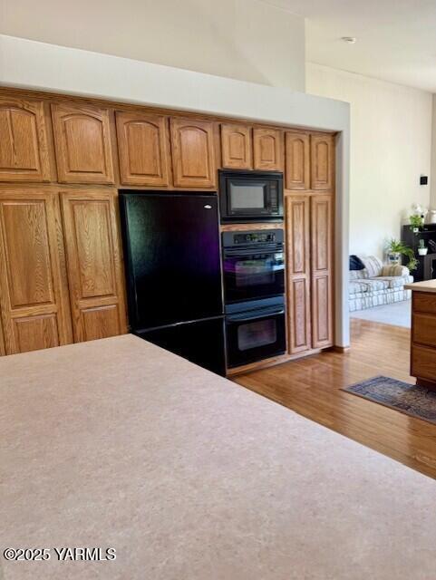 11705 Wide Hollow Rd, Yakima, WA 98908 - kitchen featuring black appliances, wood finished floors, light countertops, and brown cabinetry