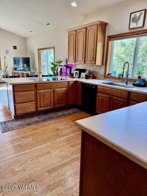 11705 Wide Hollow Rd, Yakima, WA 98908 - kitchen with black appliances, a sink, a peninsula, light wood finished floors, and light countertops