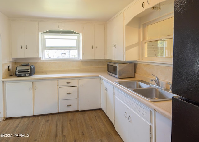 2002 Landon Ave, Union Gap, WA 98903 - kitchen with stainless steel microwave, freestanding refrigerator, a sink, white cabinets, and light wood finished floors