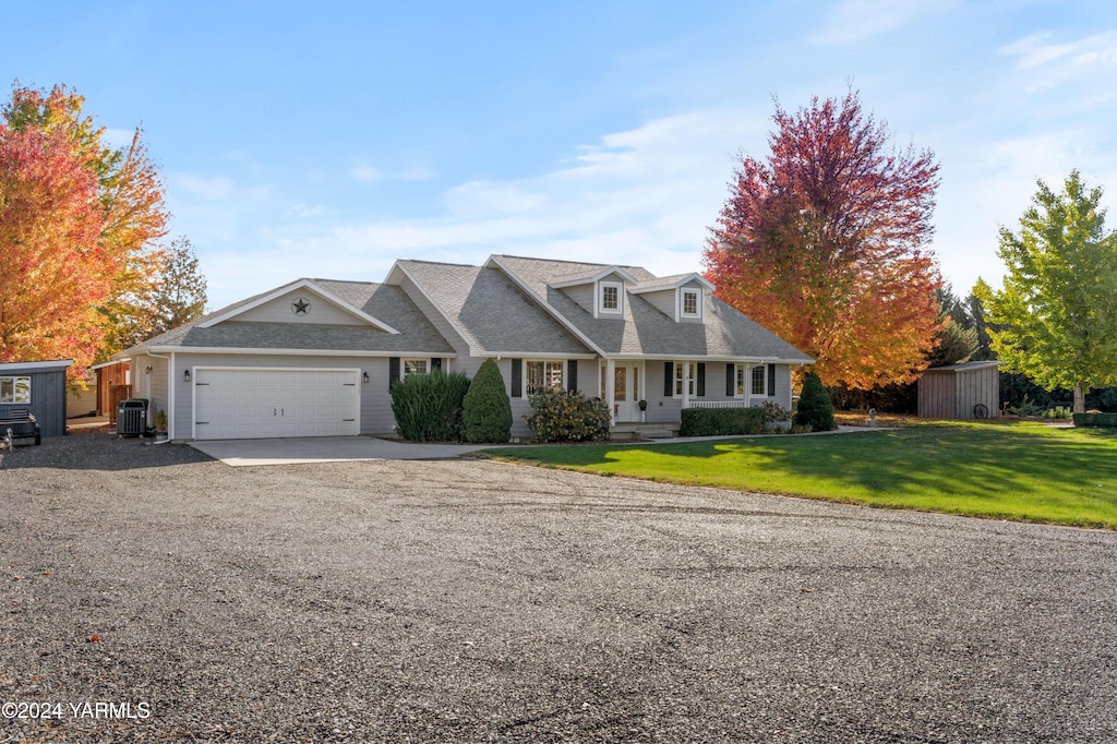 view of front of house featuring a porch, central air condition unit, a garage, a front yard, and gravel driveway