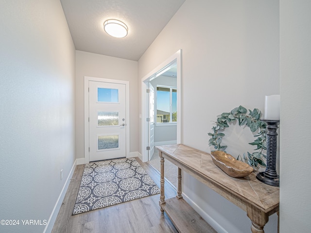 doorway with light wood-style flooring and baseboards