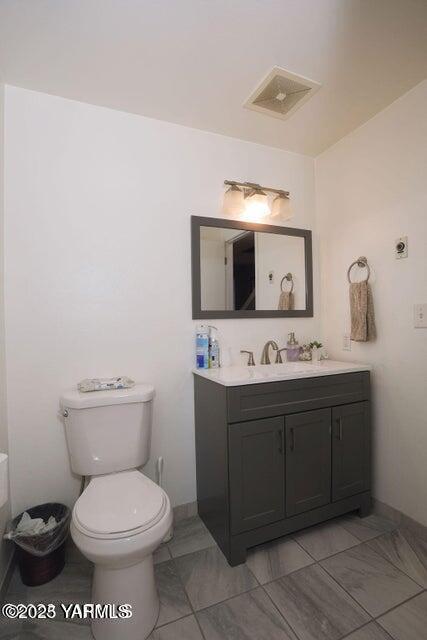 6504 Terry Ave, Yakima, WA 98908 - bathroom with toilet, baseboards, visible vents, and vanity