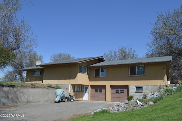 view of front of house with a garage, aphalt driveway, and a chimney