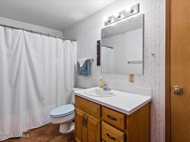bathroom with vanity, toilet, and wallpapered walls