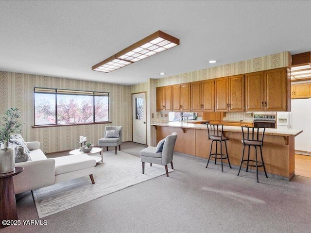 living area featuring recessed lighting, wallpapered walls, and light carpet