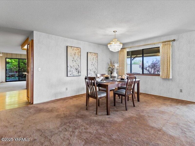 dining room with a chandelier, wallpapered walls, a textured ceiling, and carpet