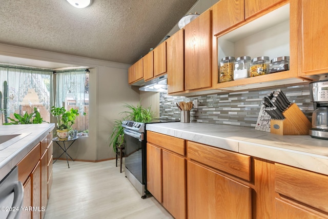 kitchen featuring tile counters, light wood-style flooring, backsplash, and stainless steel appliances