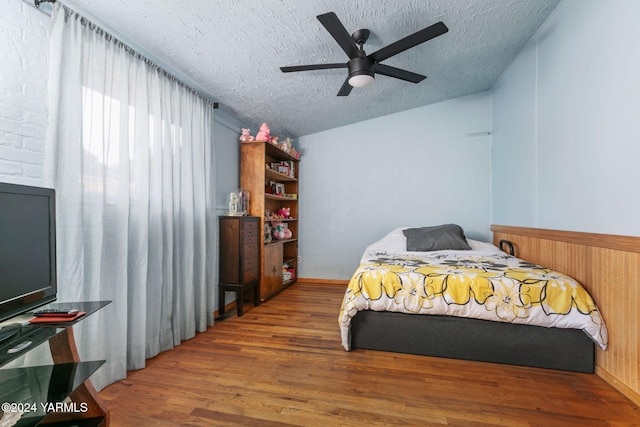 bedroom with lofted ceiling, a textured ceiling, and wood finished floors