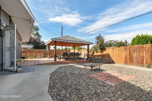 view of patio with a deck, a gazebo, a fenced backyard, and an outdoor fire pit