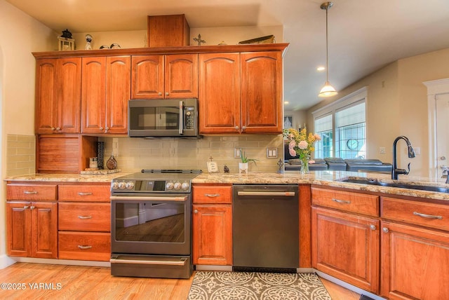 11300 Flintstone Rd, Yakima, WA 98908 - kitchen featuring appliances with stainless steel finishes, tasteful backsplash, light wood-type flooring, and brown cabinetry
