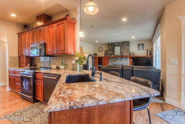 11300 Flintstone Rd, Yakima, WA 98908 - kitchen featuring stainless steel appliances, light stone countertops, arched walkways, light wood finished floors, and a peninsula