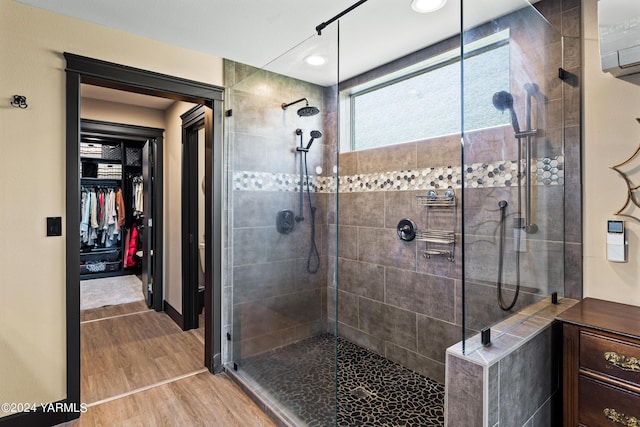 full bath with wood finished floors, walk in shower, and a walk in closet