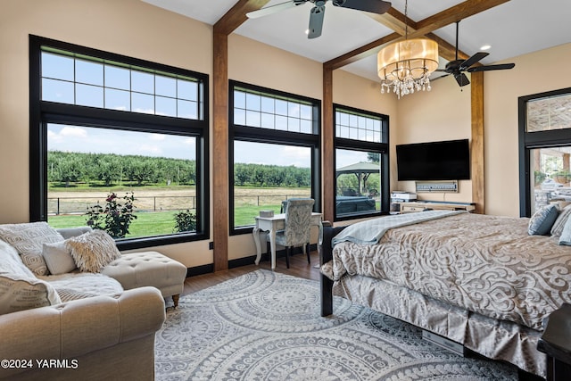 bedroom featuring ceiling fan with notable chandelier, beam ceiling, and wood finished floors