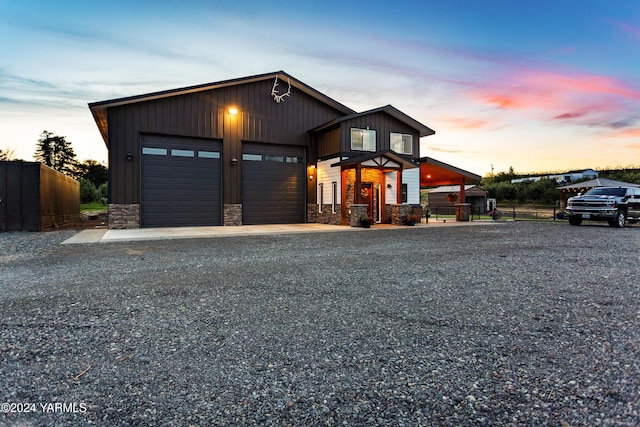 view of front of property featuring stone siding, gravel driveway, fence, and an outdoor structure