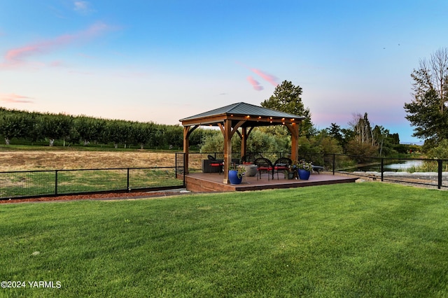 view of home's community with a water view, a yard, fence, and a gazebo