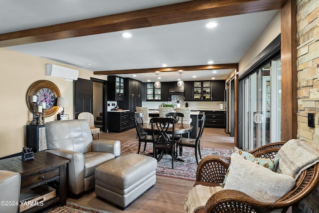 living area featuring recessed lighting, a wall mounted air conditioner, beamed ceiling, and wood finished floors