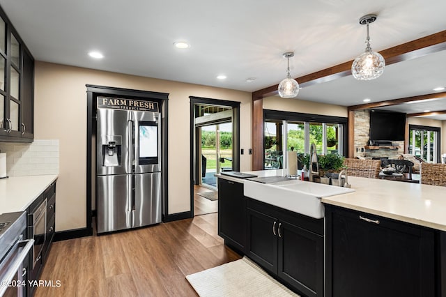 kitchen with open floor plan, light countertops, glass insert cabinets, and stainless steel fridge with ice dispenser