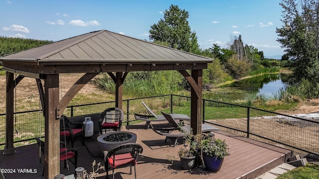 wooden deck with an outdoor fire pit, a water view, and a gazebo