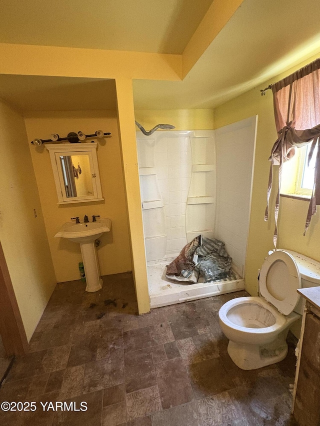 bathroom featuring toilet, a stall shower, and stone finish floor