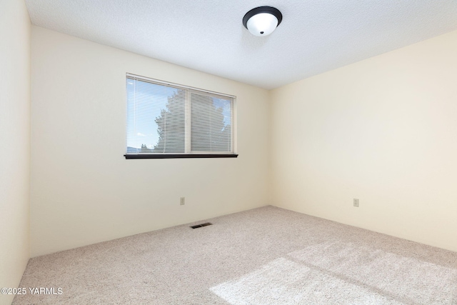 carpeted empty room with a textured ceiling and visible vents