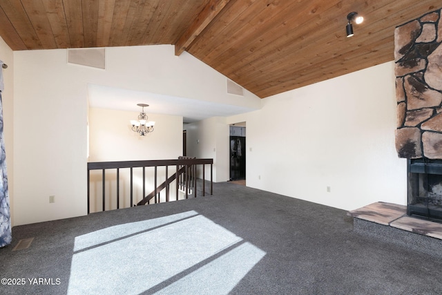 carpeted spare room featuring lofted ceiling with beams, wood ceiling, a fireplace, and a notable chandelier