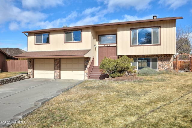 bi-level home with concrete driveway, an attached garage, fence, stone siding, and a front lawn