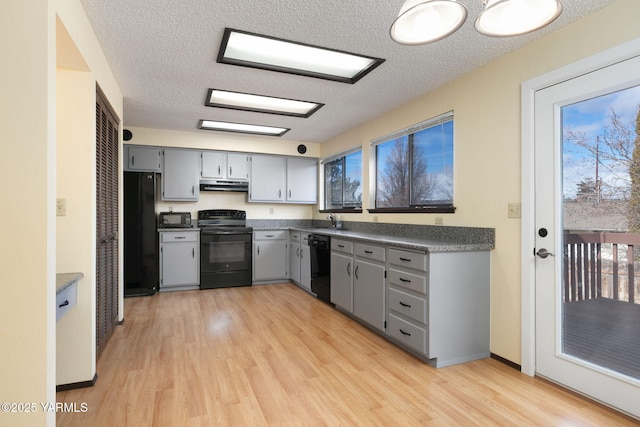 kitchen featuring gray cabinetry, a sink, under cabinet range hood, and black appliances