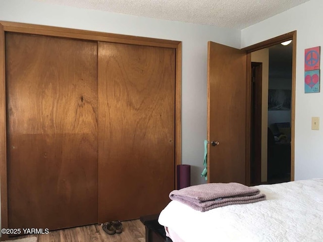 bedroom with a textured ceiling, a closet, and wood finished floors