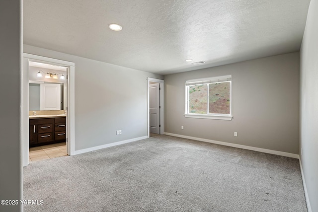 unfurnished bedroom featuring light colored carpet, baseboards, a textured ceiling, recessed lighting, and ensuite bathroom