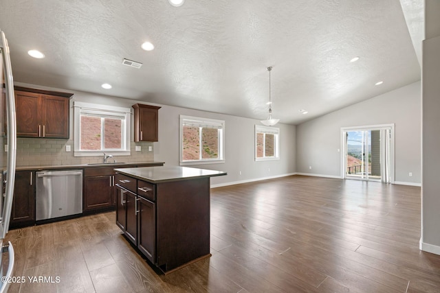 kitchen with dishwasher, a sink, decorative backsplash, a center island, and baseboards