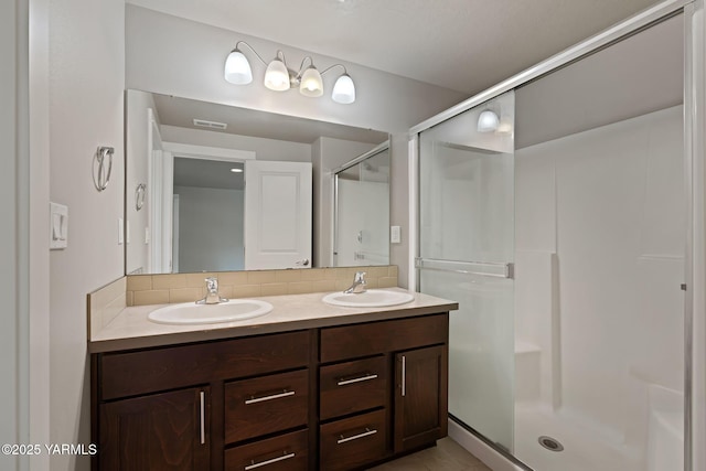 bathroom featuring backsplash, a stall shower, and double vanity