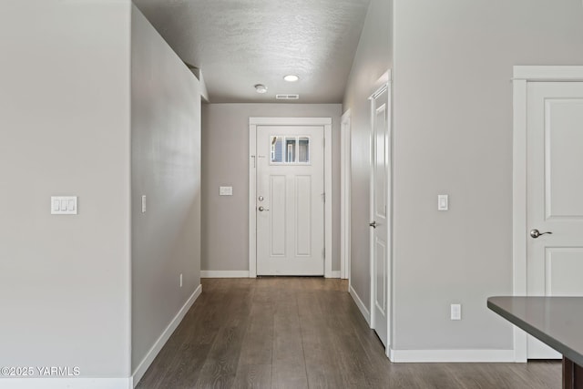 doorway featuring baseboards, a textured ceiling, and dark wood-style floors