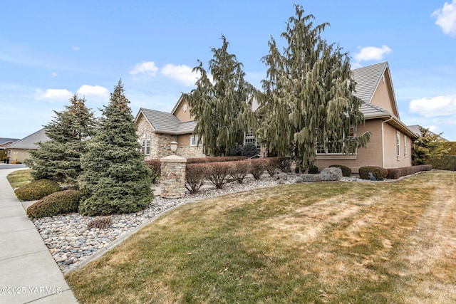 exterior space featuring stone siding, a tiled roof, a front lawn, and stucco siding