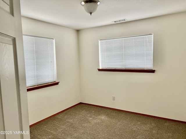 unfurnished room with carpet, visible vents, and baseboards