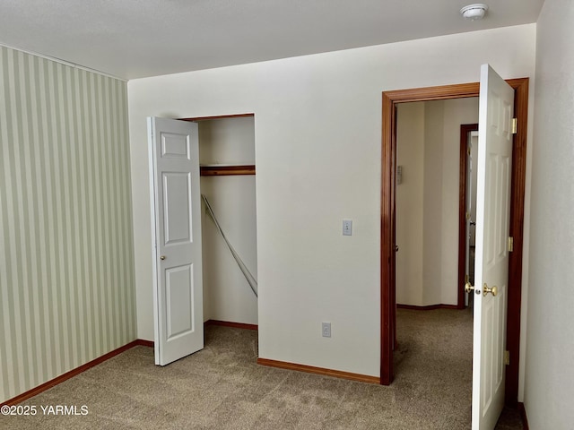 unfurnished bedroom with baseboards, a closet, and light colored carpet